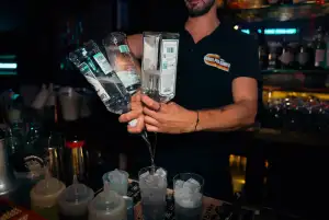 Le barman verse plusieurs bouteilles à la fois derrière le comptoir