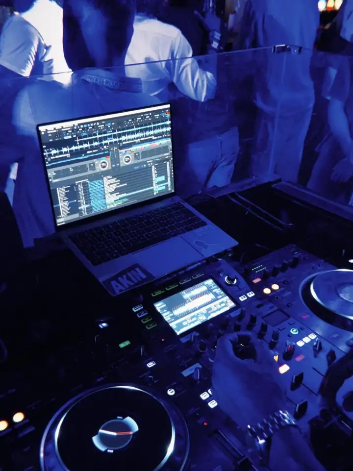 Les platines du DJ : un ordinateur portable et une table de mixage sous la lumière bleue